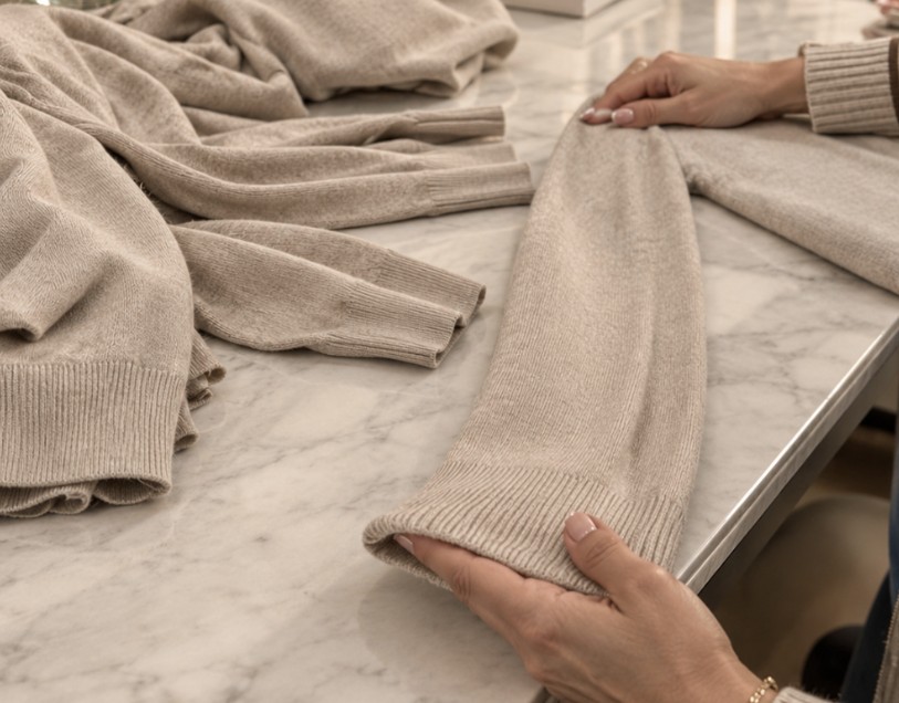 Controllo delle rifiniture di un capo in maglia beige